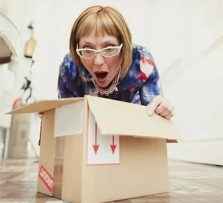 A woman peering into a cardboard box